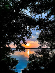 Beautiful sunset with water, sky, trees and bushes
