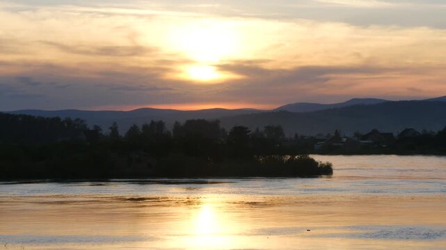 Beautiful sunset on the Selenga River with a fast current on a sunny autumn evening in Buryatia.