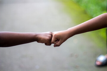 Two boys shaking hands with clenched fists and the background behind them is blurred