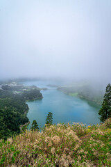 Panoramic view of Sete Cidades Lagoon, São Miguel Island, Azores, as morning clouds begin to clear, unveiling the iconic twin lakes surrounded by lush volcanic landscape.