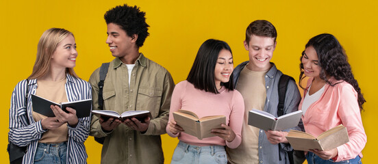 Students study in library, young people spend time together and search information. Happy generation z multiracial student read books and talk in college, isolated on orange background, studio shot