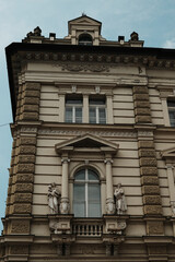 Close-up of ornate window with classical statues on a historic building in Novi Sad, Serbia. Elegant architecture with baroque elements.