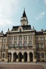 Fototapeta premium Front view of the City Hall of Novi Sad, Serbia, with its elegant neoclassical architecture and national flags.