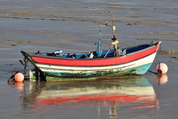 Fototapeta premium Red and White Fishing Boat Reflected in Shallow Water at Low Tide