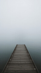 Obraz premium Wooden Dock Leading into Misty Lake Creates a Sense of Serenity and Calm in Nature