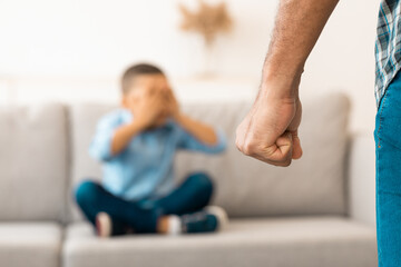 Child Abuse. Unrecognizable Black Father Clenching Fist Ready To Hit Scared Little Son Treatening Boy In Living Room At Home. Domestic Violence On Kid. Cropped, Selective Focus On Male Arm