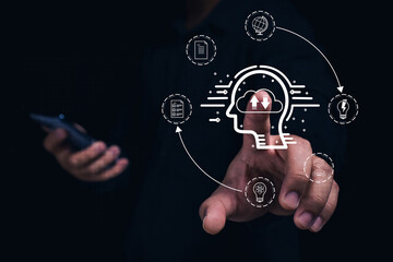 A person interacts with digital brain graphics, symbolizing technology and cognitive processes, while holding a smartphone in a dark environment.