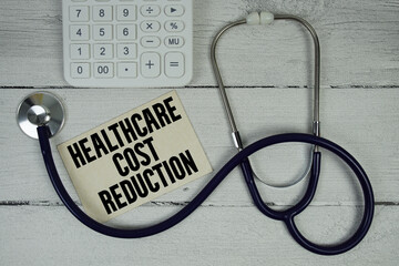 Healthcare Cost Reduction text with Stethoscope and calculator on wooden background