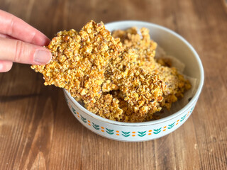 Hand Picking Up a Piece of Homemade Granola Bark from a Bowl