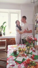 Romantic married couple dancing at home near the window against a background of flowers