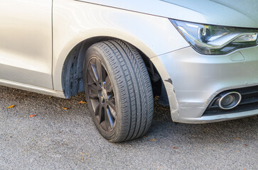 Deep scratches on the front part of a car near the wheel showing extensive paint damage and surface wear