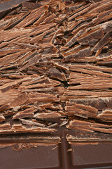 A textured close-up features a generous pile of irregular dark chocolate shavings, perfect for culinary applications or as a delightful topping