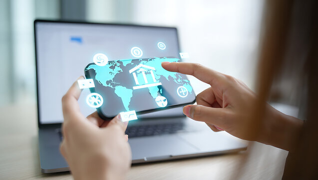 Hands touching smartphone displaying global finance icons over laptop technology