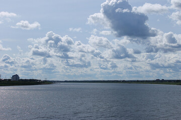 Wide river Tom landscape in natural photography style, blue and green tones, expansive water views and cloud-filled sky, Tomsk, Russia, Siberia