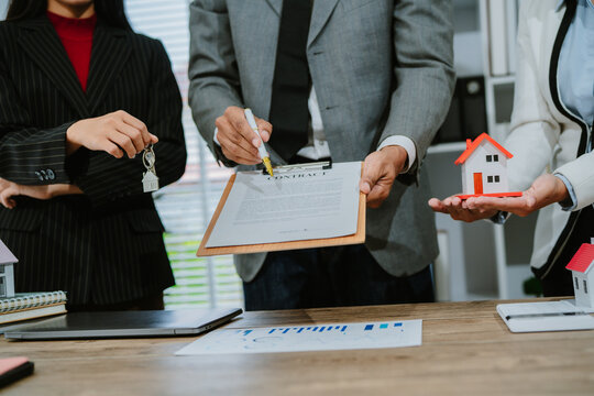 Young couple shaking hands with real estate agent after finalizing their contract, celebrating the exciting purchase of their new home - Powered by Adobe
