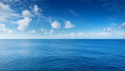 Obraz premium vast blue ocean under a sunny sky with fluffy white clouds and calm water stretches to the horizon creates tranquil scene