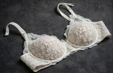Elegant white lace bralette on dark background. Delicate floral pattern, intricate detailing, sheer fabric. Feminine lingerie for sensuality and style. Perfect for fashion, romance, and beauty.