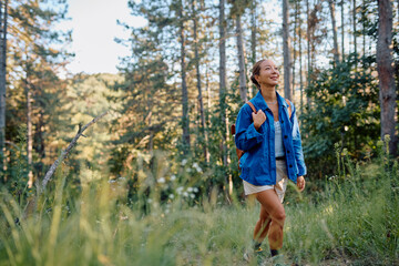 Young woman tourist exploring nature during summer holidays, walking in forest and enjoying beautiful sunny day