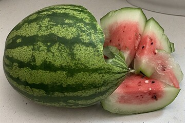 Whole and slice of ripe watermelon, heap of watermelon slices as background