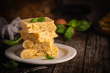 Spanish omelette with potatoes and onion, typical Spanish cuisine. Tortilla espanola. Omelet with eggs, potatoes and onion, authentic recipe. Rustic dark background