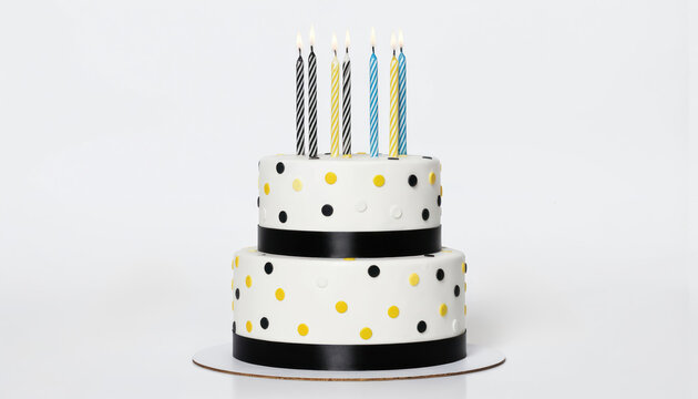 Two-tiered birthday cake decorated with colorful polka dots, black ribbons. Lit candles, including striped black white yellow, blue, adorn top tier. Perfect for celebrations, anniversaries, festive