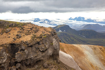 Rugged cliffs overlook expansive valleys and snowy peaks in Iceland's breathtaking landscapes