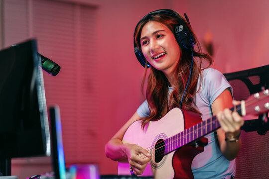 Musician woman playing acoustic guitar live streaming music content from home studio setup online entertainment