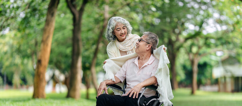 Senior couple finds peaceful outdoor joy park setting man in wheelchair woman provides comforting blanket warmth
