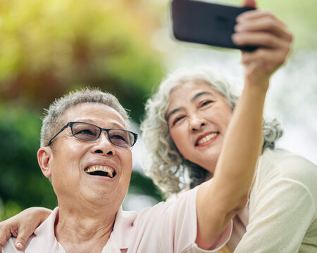 Elderly couple joyful taking selfie with smartphone in nature park capturing happiness together
