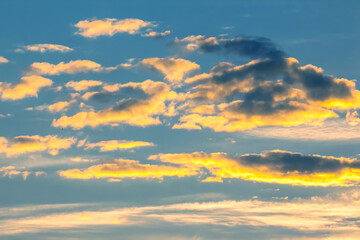 Vibrant sunset clouds illuminated by golden light in the evening sky above the horizon