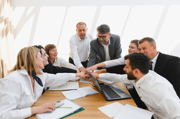Business team joining hands during meeting celebrating success