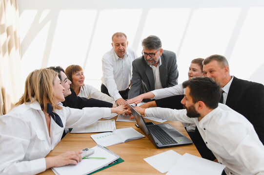 Business team joining hands during meeting celebrating success