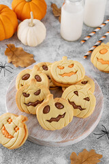 Halloween pumpkin shaped sandwich cookies with sweet cream filling on a wooden board with milk on a concrete background. Jack o lantern cookies.