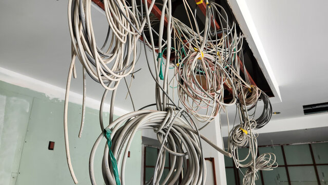 Electrical and Data cables hanging from the workplace ceiling made decorative arrangements