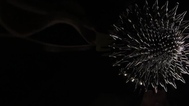 Ferrofluid experiment forming a rotating flower-like shape in dark liquid