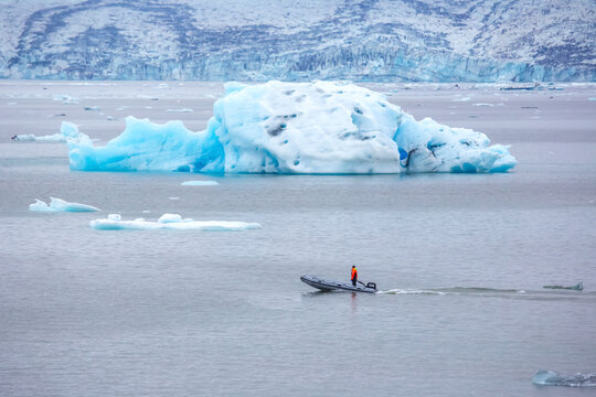 Boat navigating icy waters near glacier icebergs in Iceland