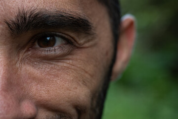 A closeup shot of a man's face, focusing on his smiling eye, eyebrow, and wrinkles