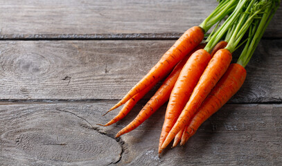 Fresh carrots bunch on a wooden background. Close up. Copy space.