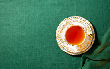 Cup of tea on a green textile cloth. Copy space. Top view.