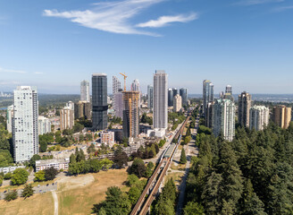 Fototapeta premium Aerial View of Burnaby Skyscrapers with SkyTrain and Forest in Greater Vancouver