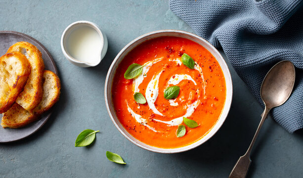 Tomato soup with cream in a white bowl on grey background. Close up. Top view.