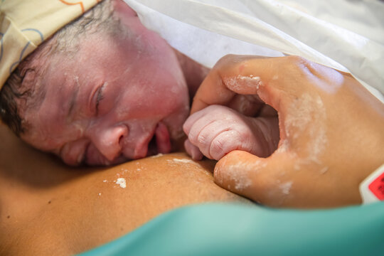 Newborn baby resting peacefully on anonymous mother's chest