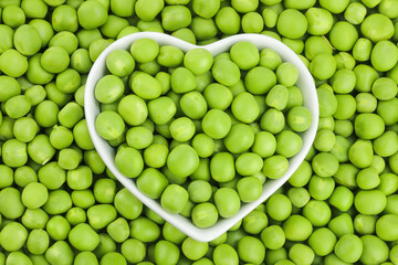 Fresh green peas in white ceramic bowl as a background. Top view. Flat lay