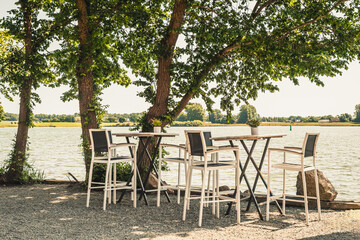 Obraz premium Bar stools and tables on the bank of a river