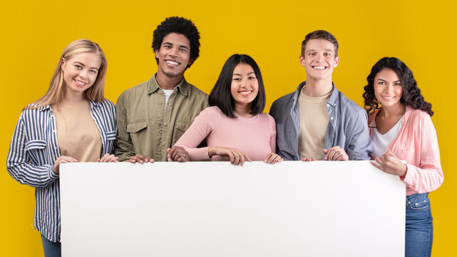 Education, ad and student recommendations. Diverse teens cheerful international students holding big banner with free space and ready to study at college, isolated on beige background, studio shot