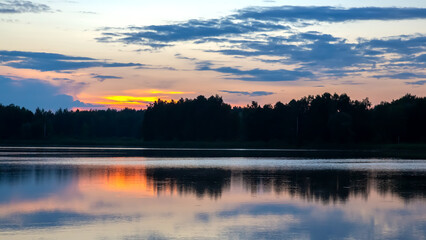Fototapeta premium Sunset reflections over a tranquil lake surrounded by lush forests