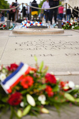 Bouquet of red flowers with French flag placed near the eternal flame at the Tomb of the Unknown Soldier under the Arc de Triomphe
