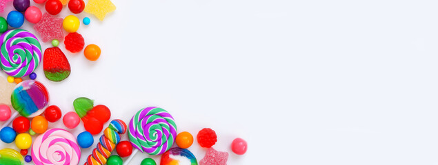 Sweet collection of candies. Top down view corner border over a white banner background.