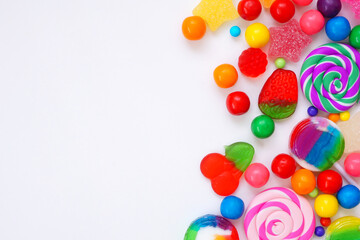Colorful collection of candies. Above view side border over a white background.