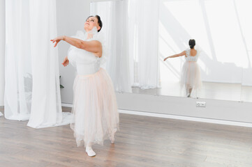 Senior ballerina practicing ballet in dance studio with mirror reflecting her elegance